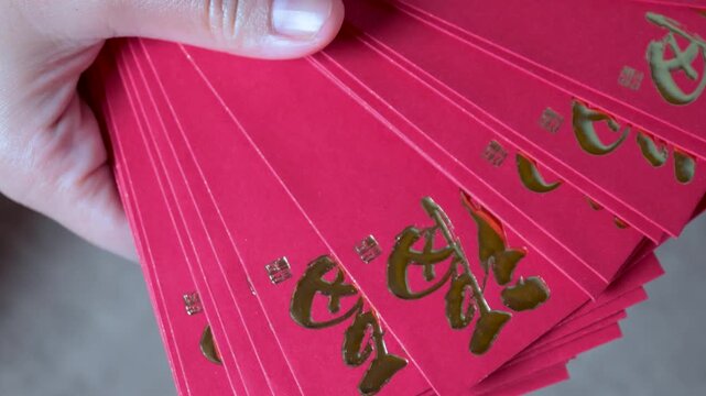 Red Envelope in Hand holding, Angpao Envelope with Golden Chinese Symbols for Lunar New Year Celebration. Traditional Lunar New Year greeting, symbol of luck, prosperity, and festive celebration