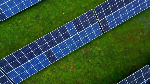 Aerial closeup of blue solar modules arranged in diagonal rows across a green field, showing clean-energy infrastructure and modern renewable power generation.