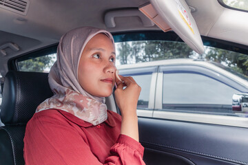 An Indonesian Muslim woman putting on her makeup while traveling by car