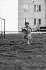 Young girl with a teddy bear running joyfully across a grassy field, wearing a light dress and sneakers, capturing the essence of childhood playfulness and freedom