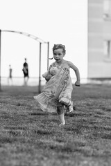 Young girl with a teddy bear running joyfully across a grassy field, wearing a light dress and sneakers, capturing the essence of childhood playfulness and freedom