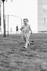 Young girl with a teddy bear running joyfully across a grassy field, wearing a light dress and sneakers, capturing the essence of childhood playfulness and freedom