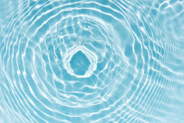 Blue water with ripples on the surface. Defocus blurred transparent blue colored clear calm water surface texture with splashes and bubbles. Water waves with shining pattern texture background.