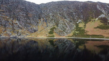 Fototapeta premium Aerial view of Llyn Eigiau with dark water beneath steep rocky slopes