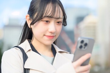 オフィス街でスマホを使用する日本人ビジネスウーマン