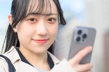オフィス街でスマホを使用する日本人ビジネスウーマン