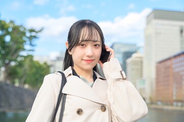 オフィス街でスマホを使用する日本人ビジネスウーマン