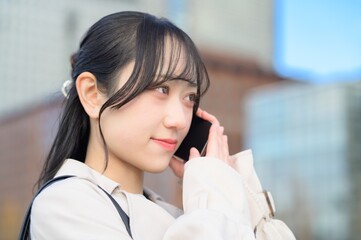 オフィス街でスマホを使用する日本人ビジネスウーマン