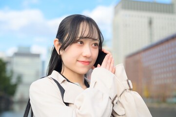 オフィス街でスマホを使用する日本人ビジネスウーマン