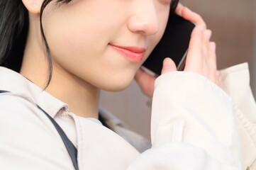 オフィス街でスマホを使用する日本人ビジネスウーマン