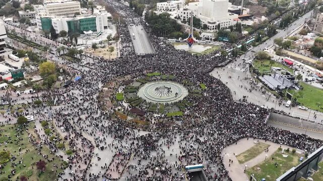 An aerial view of thousands of Syrians celebrating the end of the war in Damascus, carrying Syrian flags.