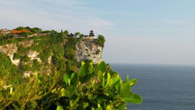 Temple crowns Uluwatu cliff above the Indian Ocean on Bali, Indonesia, slow left pan.