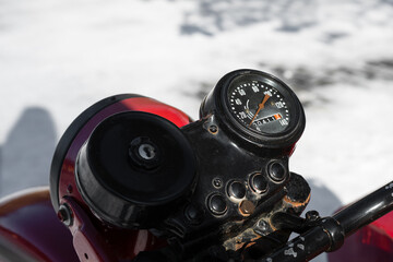 Closeup photo of a round black speedometer of an old retro motorcycle