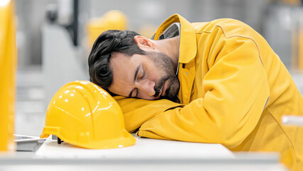 Stressed industrial worker with head down fatigue and burnout concept. Worker resting with helmet in industrial environment.