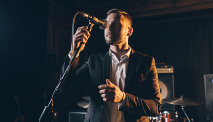 Man in formal attire performing with a microphone on stage.