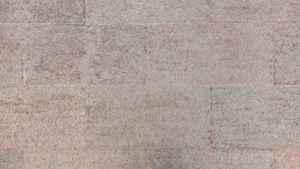 Natural brown and gray granite stone wall texture background. Rough square masonry tiles surface pattern for architecture, flooring, or design backdrop.