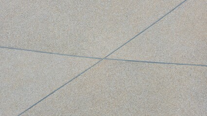 The walkway surface is made of exposed aggregate concrete with beige, gray, and light brown stones. The rough natural texture features straight gray grout lines forming an abstract geometric pattern.
