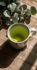 Green tea in a mug with eucalyptus leaves on a wooden table.