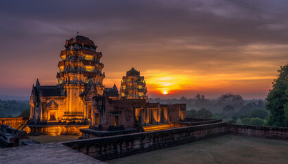 Obraz premium Ancient temple complex illuminated at sunset amidst lush greenery.