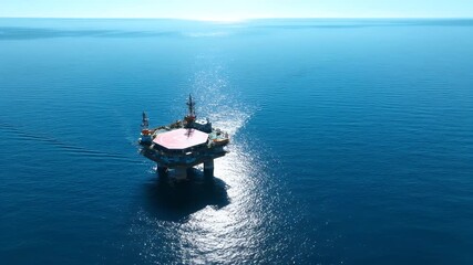 Offshore oil rig platform floating on calm blue ocean water under clear sky.