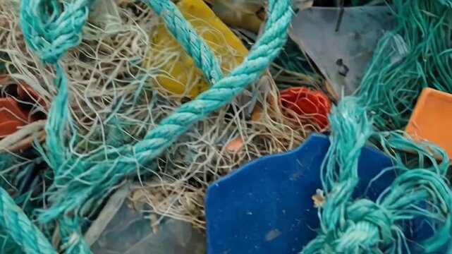 Close-up of tangled plastic waste and fishing nets. Colorful marine debris pollution with ropes and bottle caps. Environmental garbage texture