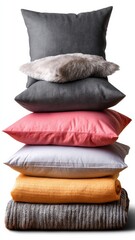Stack of decorative pillows on a folded blanket with diverse textures and colors against a neutral background