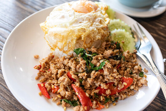 Spicy Thai basil stir-fried with minced beef and crispy fried egg on top of steamed rice, authentic Pad Kra Pao beef served with chili and garlic, popular Thai street food concept.