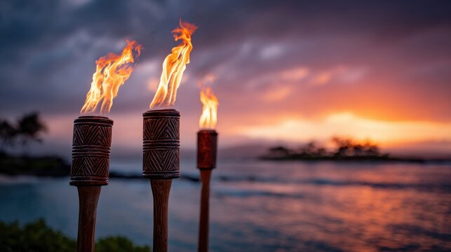 Burning tiki torches illuminate a tropical beach at sunset with fiery flames