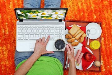 top view of person working on laptop with coffee and snacks on colorful desk