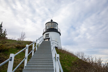 Lighthouse on the hill with stairs leading up under cloudy sky