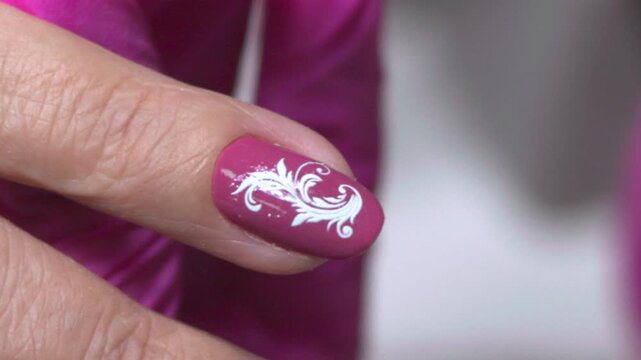 Elegant Nail Detail, Studio Shot Emphasizing Detailed White Swirl Design On Mauve Painted Nails Of Hand. Media