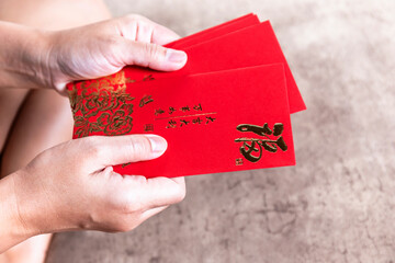 Hands holding red envelopes hongbao for giving, Angpao with gold (Fu) symbol, symbolizing...