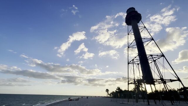 Sanibel Island Light, also known as Point Ybel Light, stands tall on the sandy beach against a clear blue sky, inviting tourists to explore the natural beauty of Sanibel, Florida