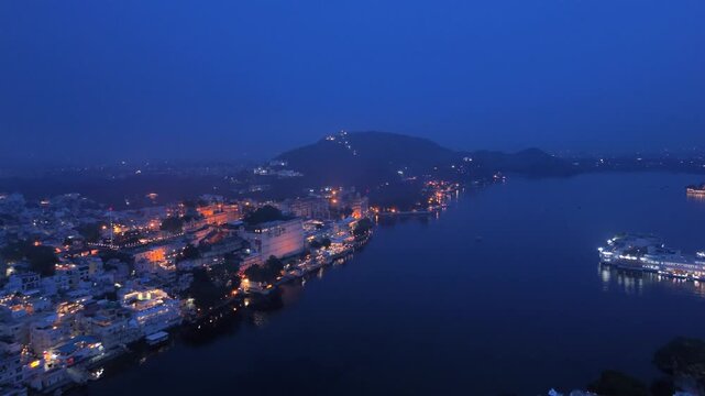 Udaipur City Palace illuminated in golden light during blue hour, copy space. Rajasthan, India.