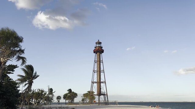 Sanibel Island Light, also known as Point Ybel Light, stands tall on the sandy beach against a clear blue sky, inviting tourists to explore the natural beauty of Sanibel, Florida