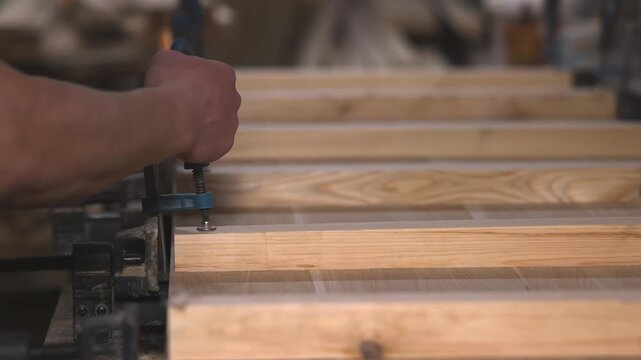 Steady Hands Press Clamp Onto Assembled Planks, Repeated Hand Motion Secures Glued Edges Of Wooden Boards. Media