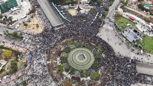 An aerial view of thousands of Syrians celebrating the end of the war in Damascus, carrying Syrian flags.
