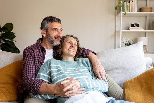 Mature couple relaxing on sofa looking into distance