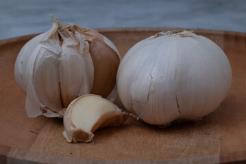 Fresh garlic is placed in a mortar and pestle on a marble-patterned wooden table.