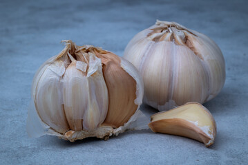 Fresh garlic is placed on a marble patterned wooden table.