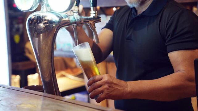 Bartender pouring draft beer from tap into glass at bar counter