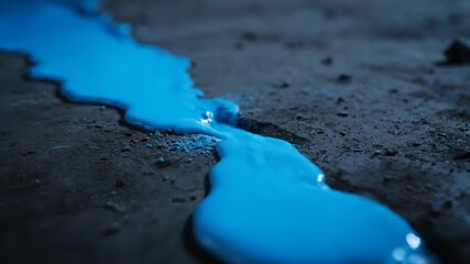 Blue Liquid Flowing Across the Ground Crack in a Dark Environment