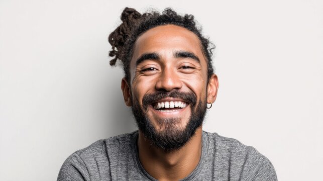 Happy man with a beard and dreadlocks smiles broadly at the camera