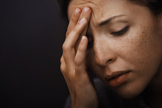 Close-up of person with headache and vulnerability touching forehead