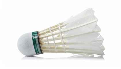 A white badminton shuttlecock with a feathered skirt and green-banded cork base rests in close-up—evoking aerodynamic elegance, sport precision, and minimalist focus in a clean visual study.