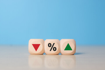 Minimal wooden blocks displaying percentage symbol with downward and upward arrows, illustrating fluctuation, comparison, statistics, inflation, deflation, and financial trends on blue background.