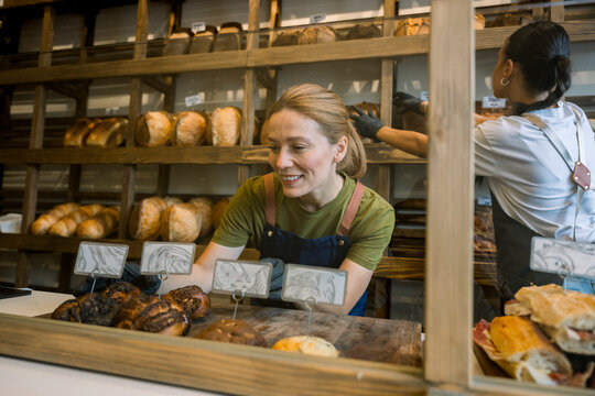 Bakery employee arranging and selling freshly baked bread at counter
