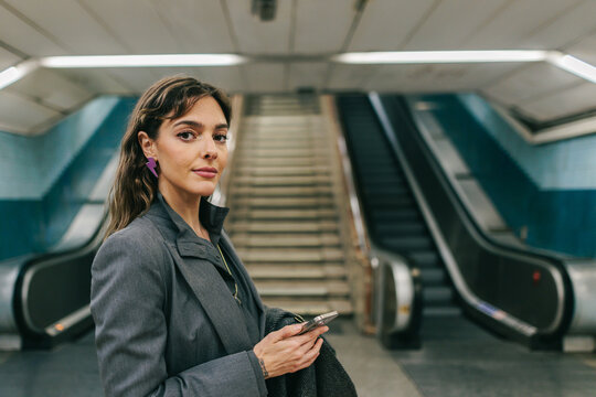 Businesswoman with phone at Madrid metro station during business commute