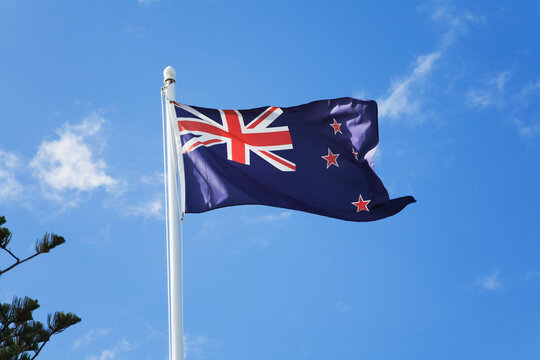New Zealand national flag waving on flagpole against blue sky