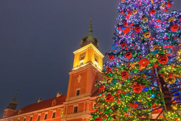 Illuminated historic residence and decorated Christmas tree in Warsaw Poland at night during winter season